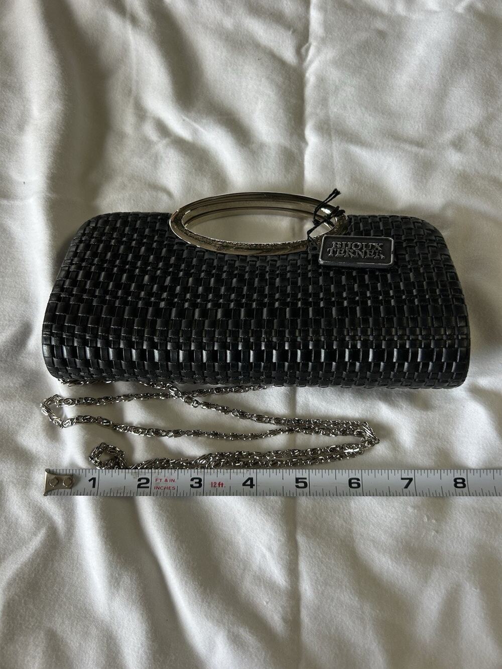 black woven Bijoux Terner clutch with a metal handle and a silver chain strap.